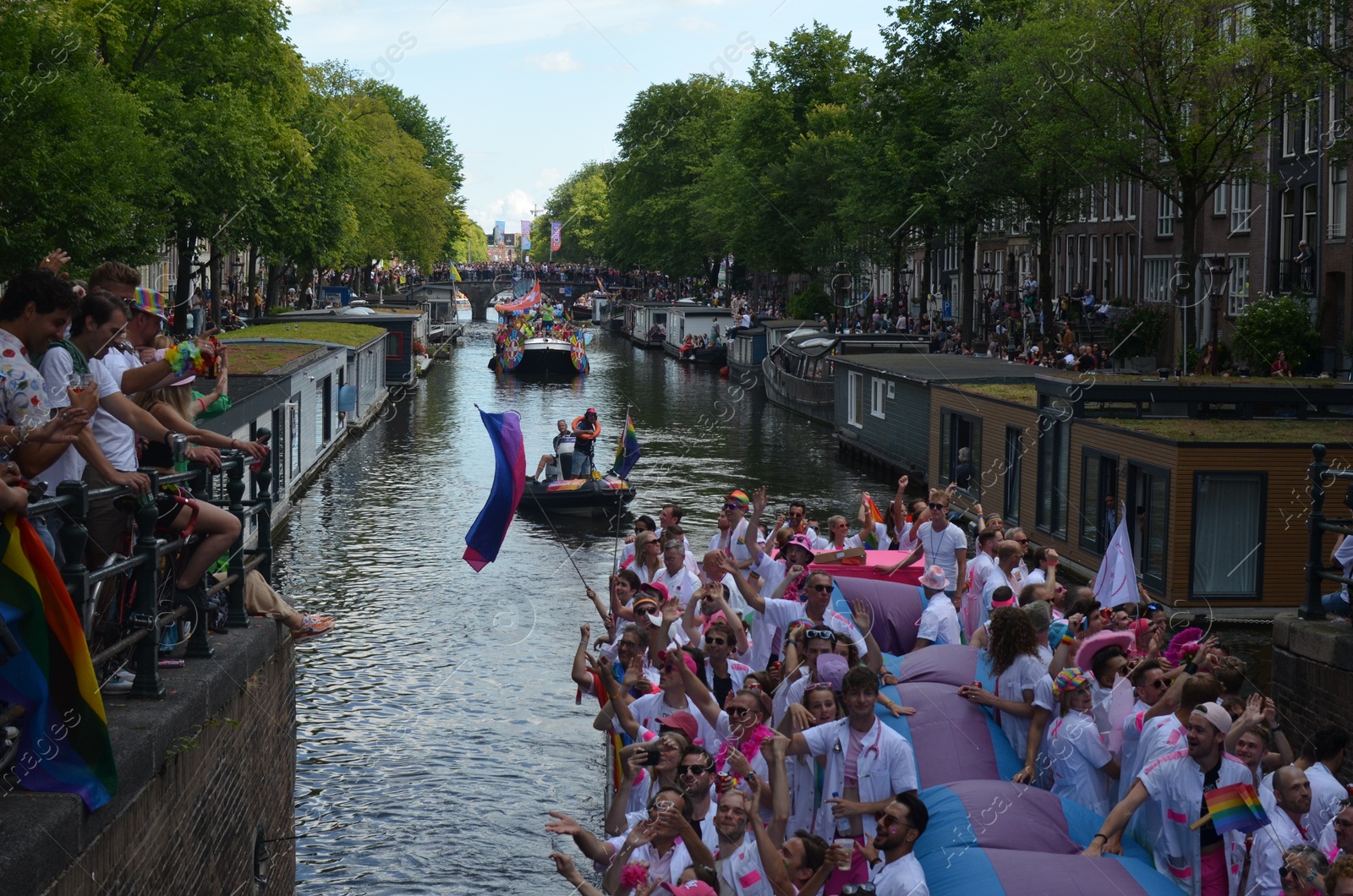 Photo of AMSTERDAM, NETHERLANDS - AUGUST 06, 2022: Many people in boats at LGBT pride parade on river