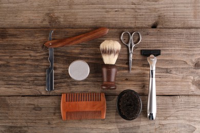 Photo of Moustache and beard styling tools on wooden table, flat lay