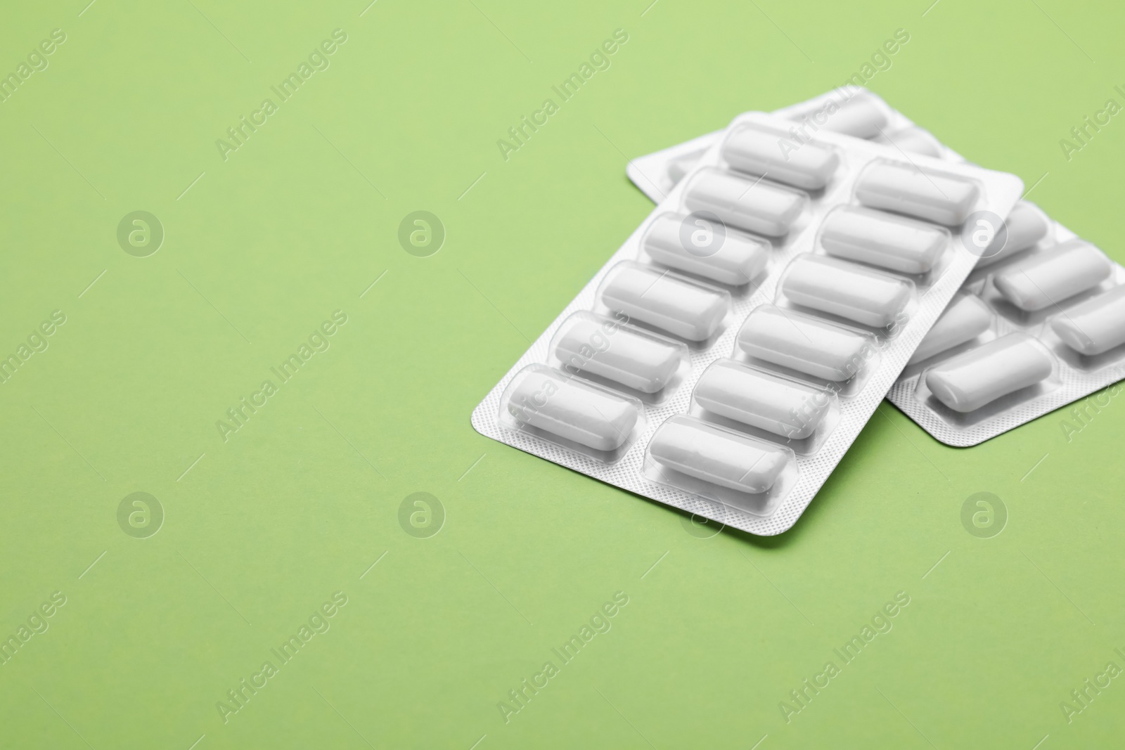 Photo of Blisters with chewing gums on pale green background. Space for text