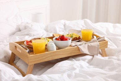 Photo of Good morning. Tray with tasty breakfast on bed at home