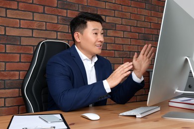 Photo of Happy boss having online meeting via computer at wooden table in modern office