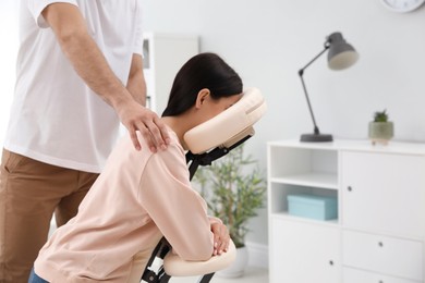 Photo of Woman receiving massage in modern chair indoors