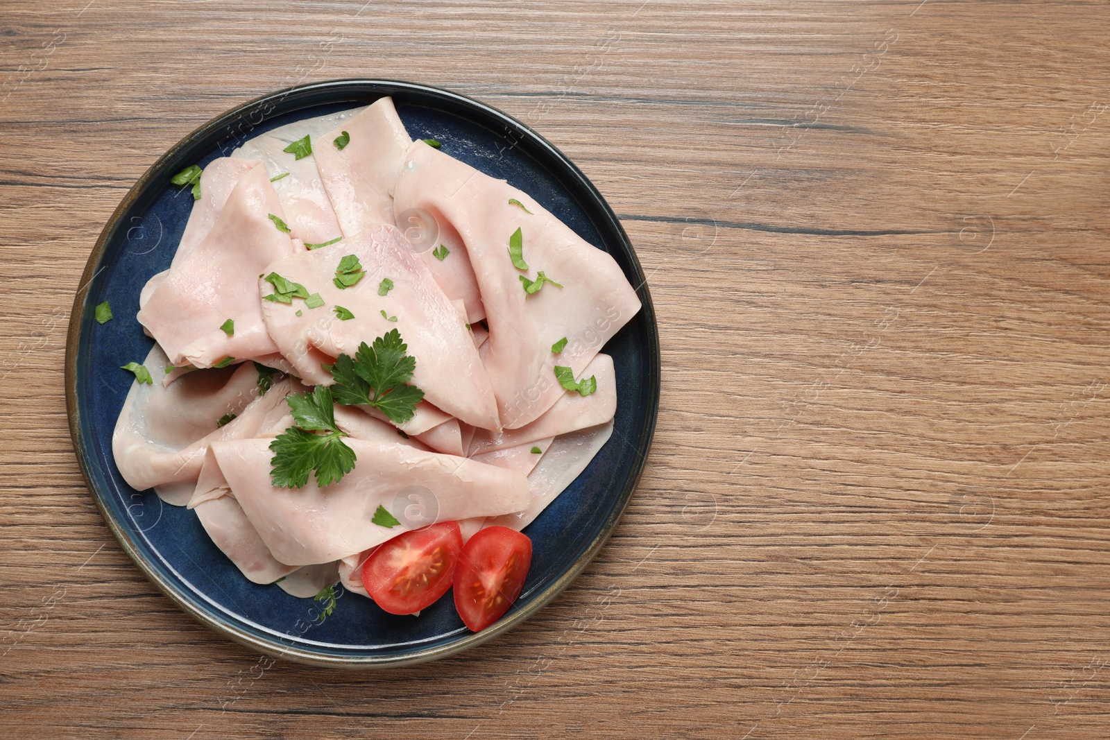 Photo of Delicious ham slices with parsley and tomato on wooden table, top view. Space for text