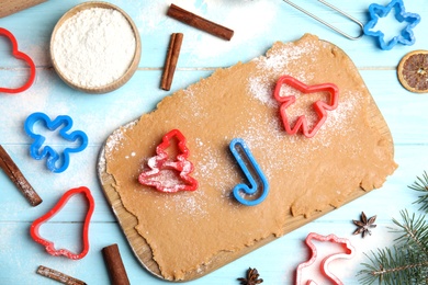 Photo of Dough, different cutters and ingredients for Christmas cookies on light blue wooden table, flat lay