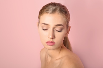 Portrait of young woman with beautiful natural eyelashes on color background