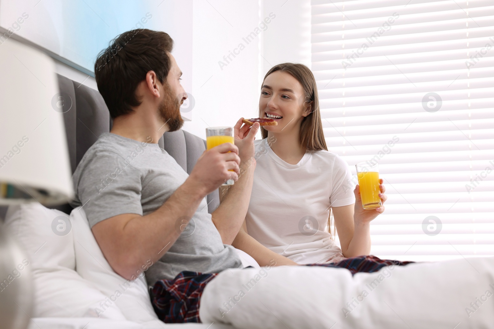 Photo of Tasty breakfast. Husband feeding his wife in bedroom