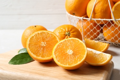 Wooden board with ripe oranges on table