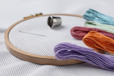 Photo of Threads and embroidery hoop with white fabric, closeup