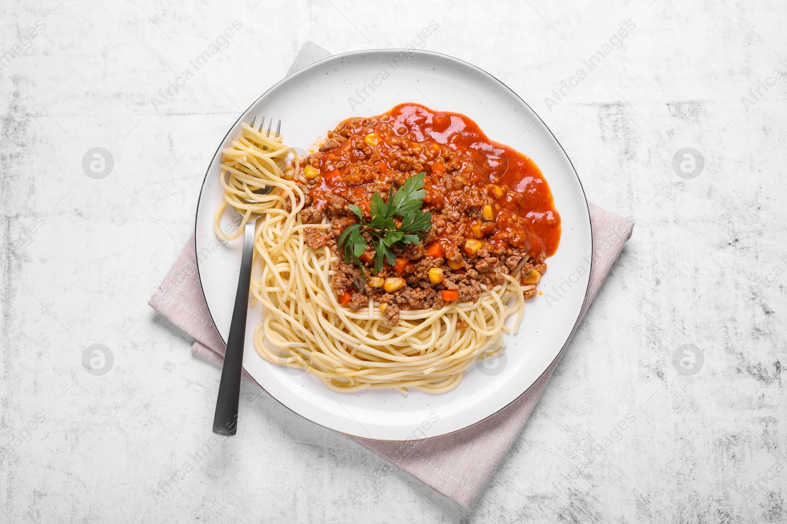 Photo of Tasty dish with fried minced meat, spaghetti, carrot and corn served on white textured table, top view
