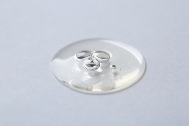 Drop of cosmetic serum on white background, macro view
