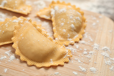 Photo of Raw ravioli on wooden board, closeup view. Italian pasta