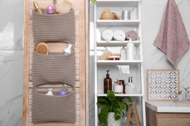 Knitted organizer hanging on wooden door in bathroom