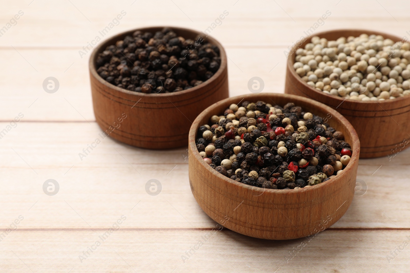 Photo of Aromatic spices. Different peppers in bowls on wooden table