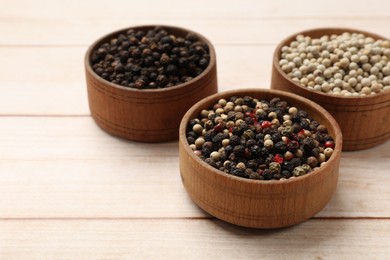 Photo of Aromatic spices. Different peppers in bowls on wooden table