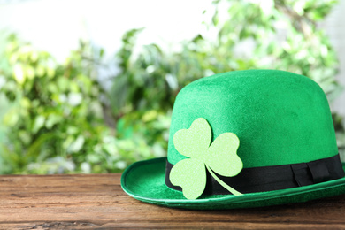 Green leprechaun hat with clover leaf on wooden table, space for text. St Patrick's Day celebration