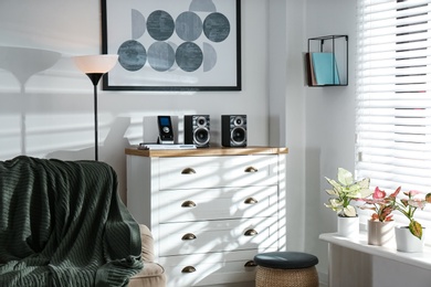 Photo of Modern audio speakers and remote on chest of drawers in living room