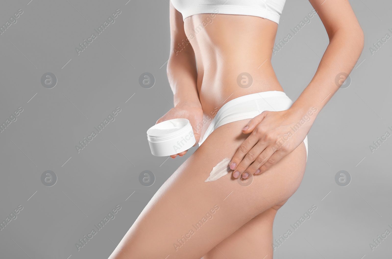 Photo of Young woman with jar of body cream on color background