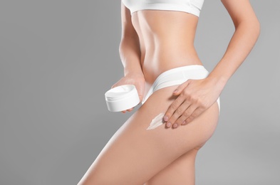 Young woman with jar of body cream on color background