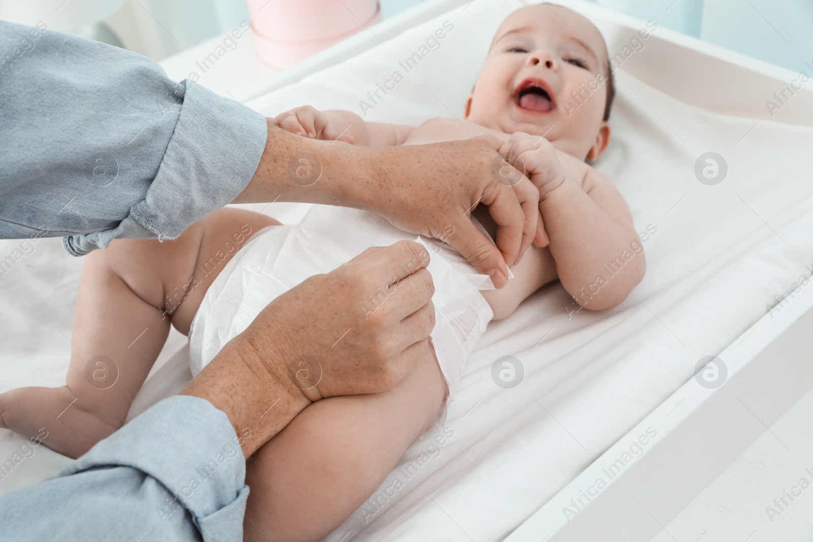 Photo of Mother changing baby's diaper at home, focus on hands