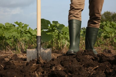 Photo of Worker digging soil with shovel outdoors, closeup