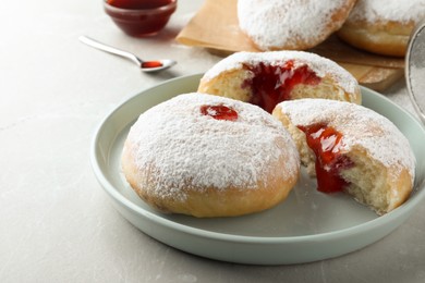 Photo of Delicious donuts with jelly and powdered sugar on light grey table, closeup