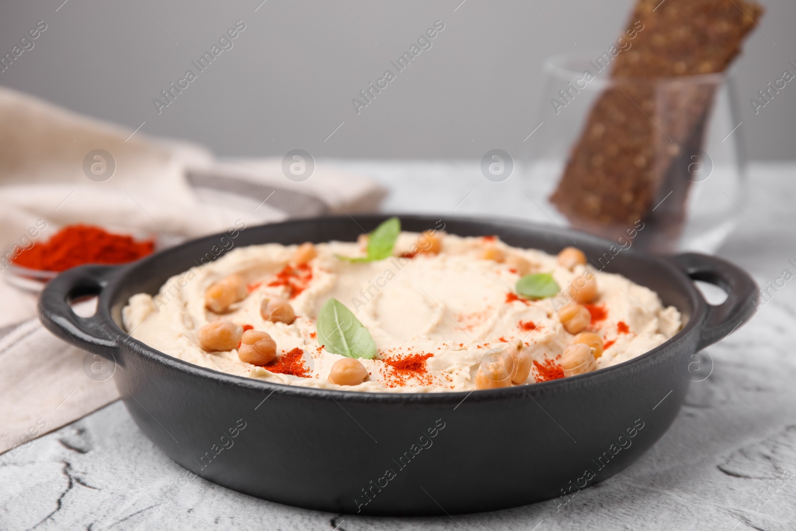 Photo of Delicious hummus with chickpeas and paprika served on white textured table, closeup