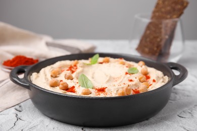 Photo of Delicious hummus with chickpeas and paprika served on white textured table, closeup