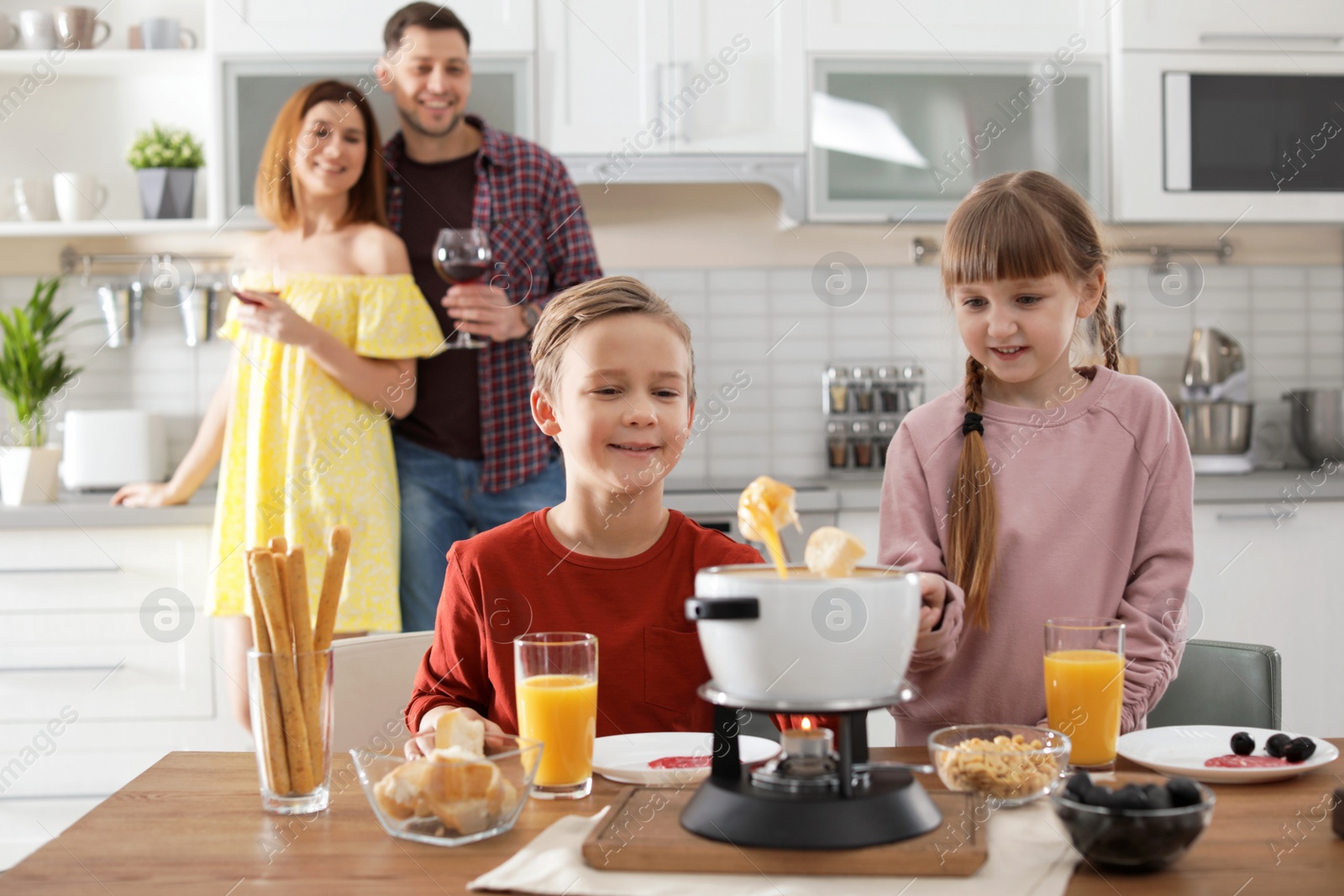 Photo of Happy kids enjoying fondue dinner at home