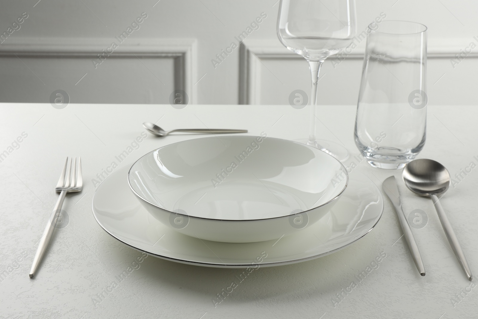 Photo of Stylish setting with cutlery and glasses on white textured table