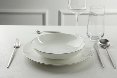 Stylish setting with cutlery and glasses on white textured table