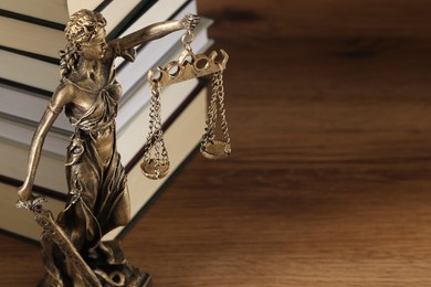 Symbol of fair treatment under law. Figure of Lady Justice and books on wooden table, closeup with space for text