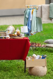 Photo of Clothing rack and table with different items on garage sale in yard