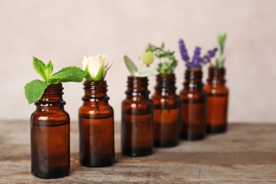 Glass bottles with different essential oils and ingredients on wooden table