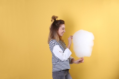 Young pretty woman with cotton candy on colorful background