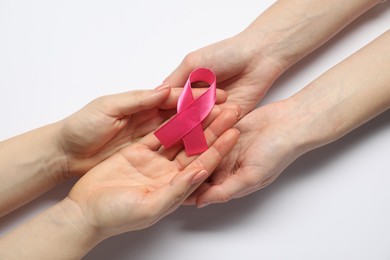 Women holding pink ribbon on white background, top view. Breast cancer awareness