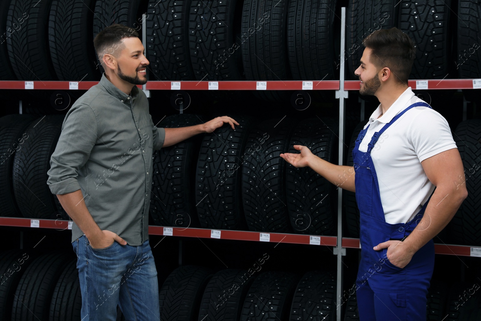 Photo of Mechanic helping client to choose car tire in auto store