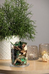 Photo of Glass jar with aromatic potpourri of dried flowers and beautiful houseplant on wooden table indoors