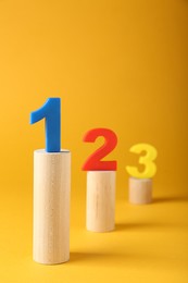 Numbers on wooden blocks against pale orange background. Competition concept