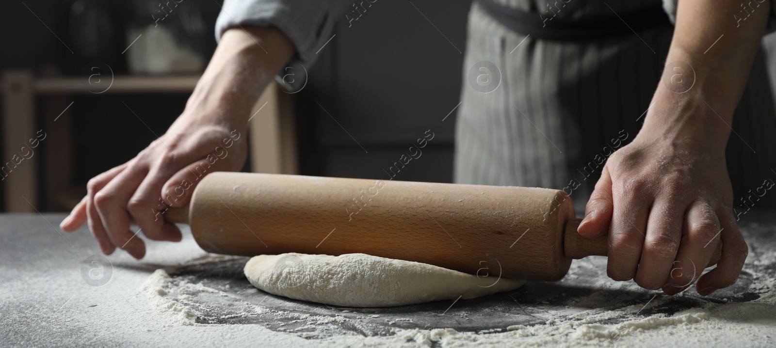 Photo of Woman rolling pizza dough with pin at table, closeup