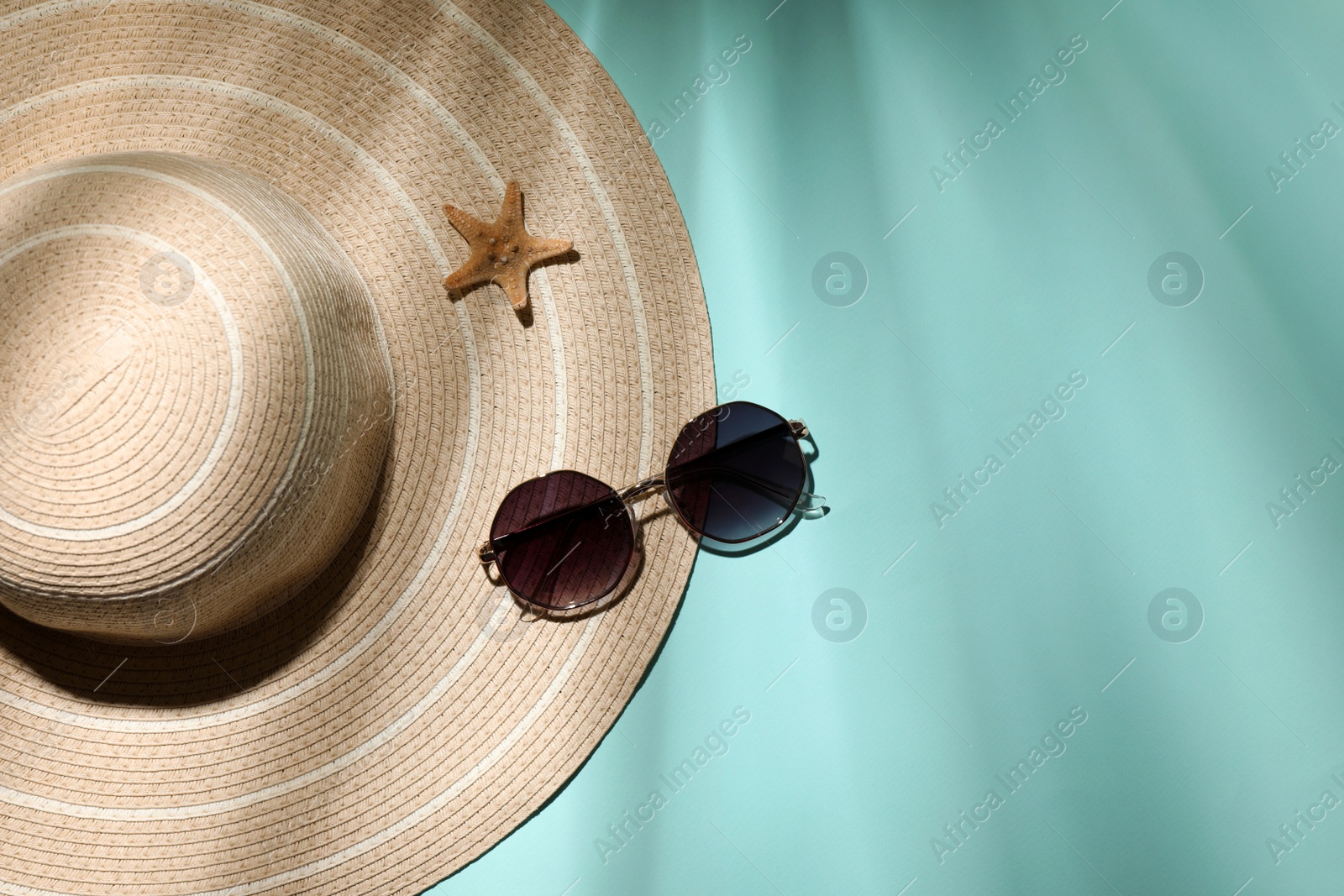 Photo of Stylish hat, starfish and sunglasses on light blue background, flat lay with space for text. beach objects