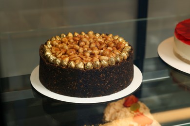 Delicious cake with nuts on counter in store, closeup