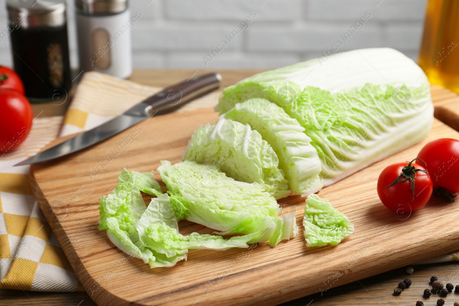 Photo of Cut fresh Chinese cabbage, tomatoes and spices on wooden table, closeup