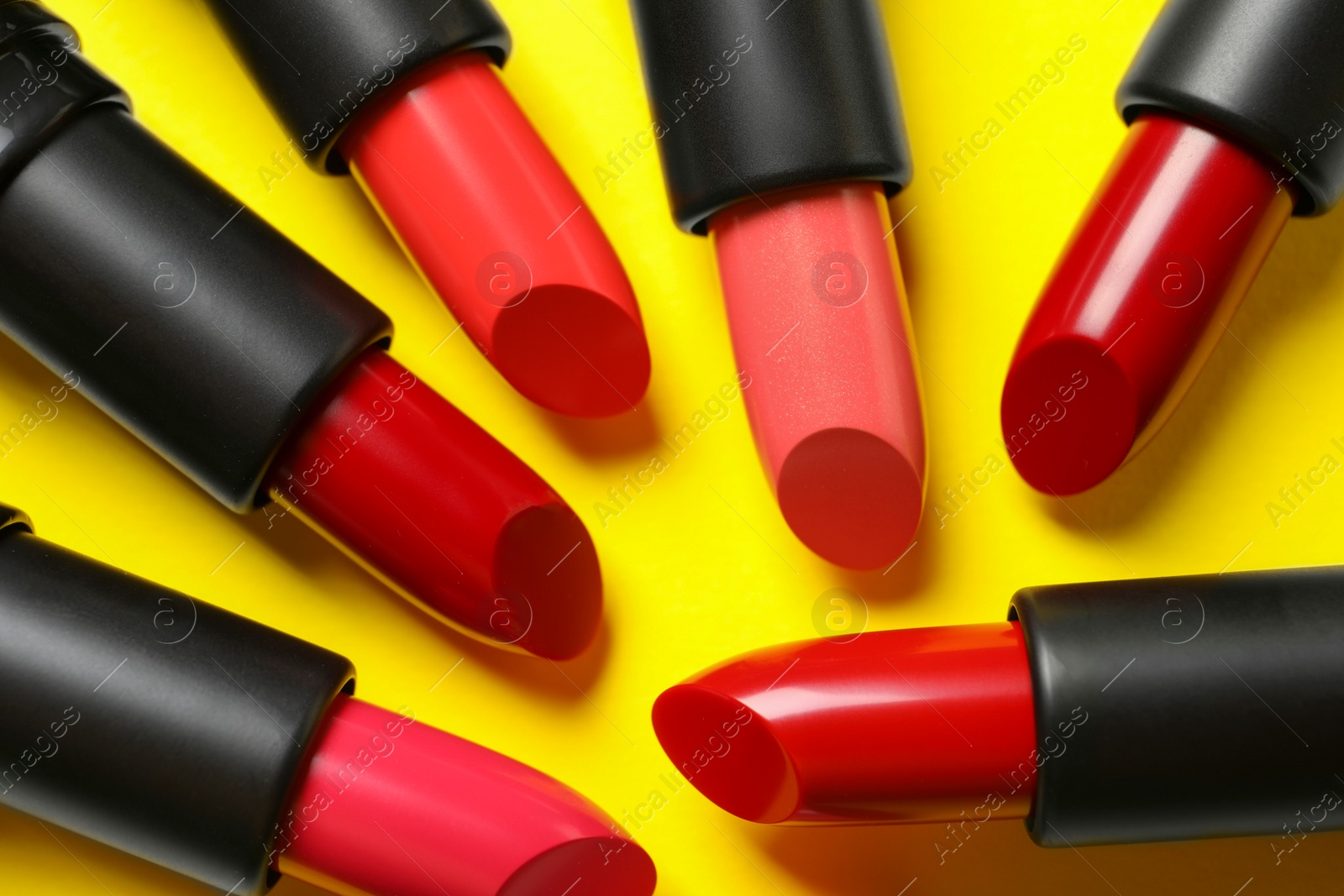 Photo of Many bright lipsticks on yellow background, flat lay