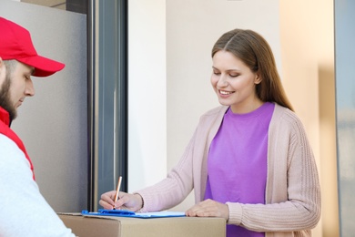 Woman receiving parcel from delivery service courier indoors