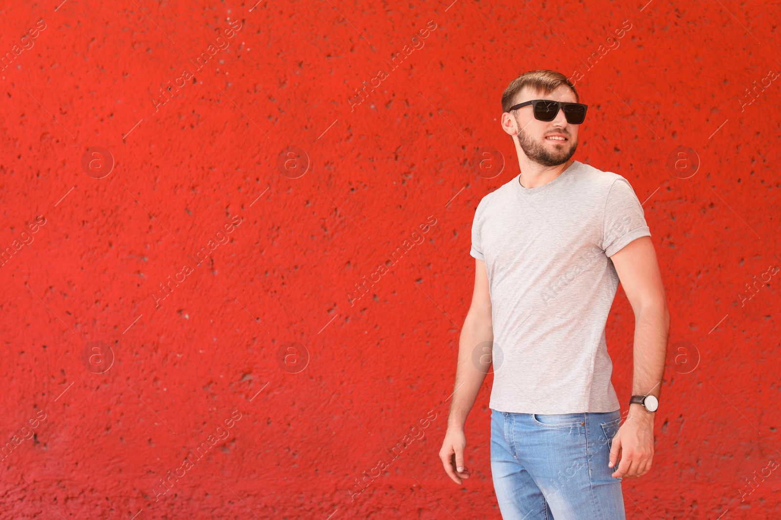 Photo of Young man wearing gray t-shirt near color wall on street