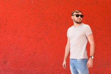 Photo of Young man wearing gray t-shirt near color wall on street