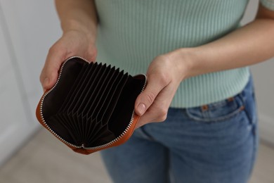 Woman with empty wallet at home, closeup