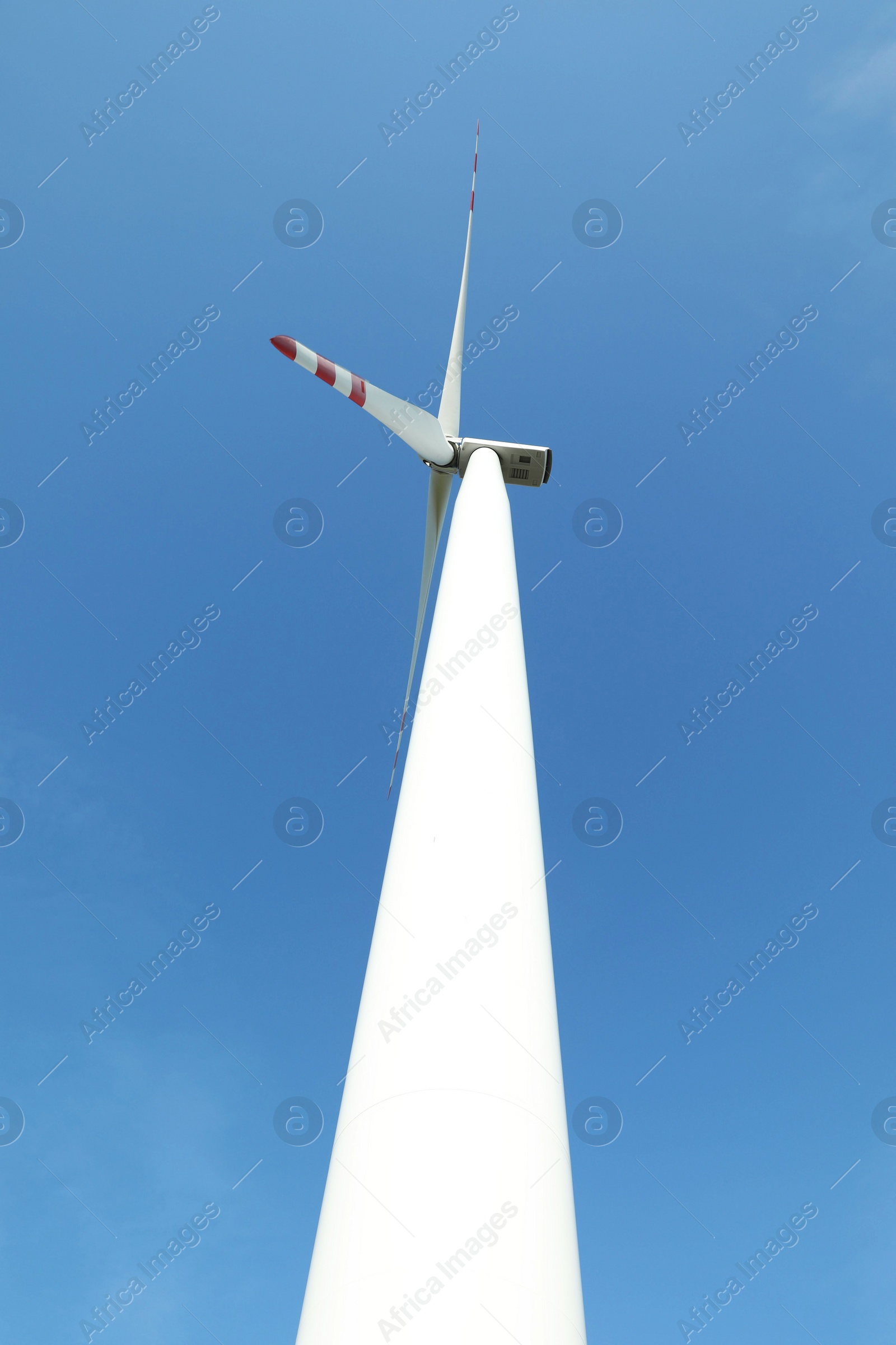 Photo of Modern wind turbine against blue sky, low angle view. Alternative energy source