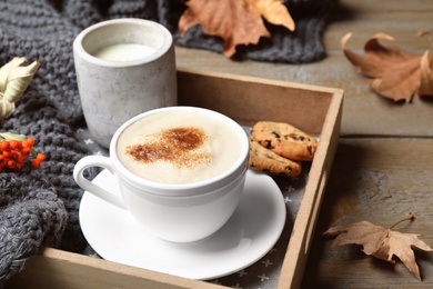 Photo of Cup of hot drink and candle on wooden table. Cozy autumn atmosphere
