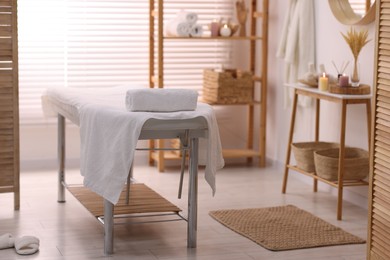 Comfortable massage table with clean towels in spa center